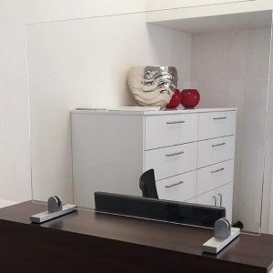 Bei der Annahme von Patienten innerhalb von bspw. Praxen kann durch eine Spuckschutzwand aus Glas der direkte Aerosolpartikelanteil reduziert werden